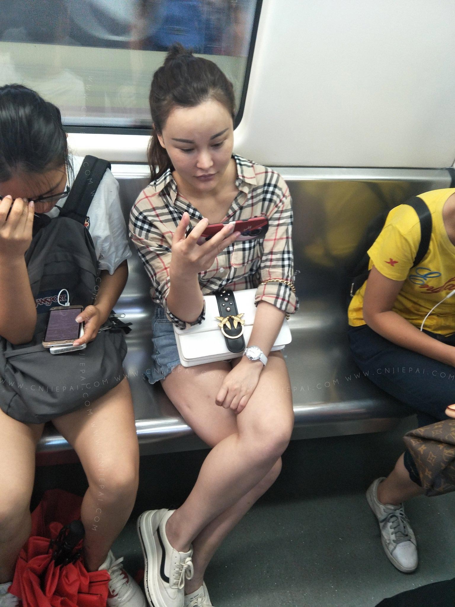 地铁上看手机的美女，脸有人工的痕迹 图1